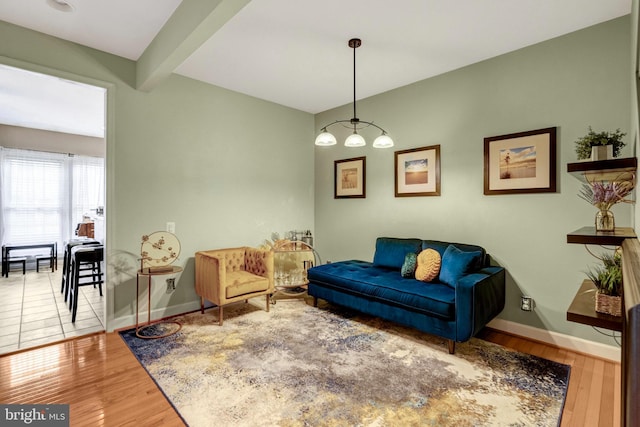 living room featuring beam ceiling, baseboards, and wood finished floors