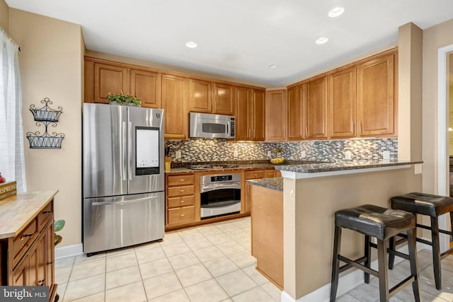 kitchen with a breakfast bar, a peninsula, brown cabinetry, and stainless steel appliances