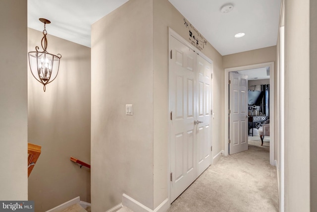 hall featuring an upstairs landing, baseboards, a chandelier, and light carpet