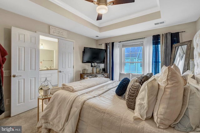 carpeted bedroom featuring a tray ceiling, visible vents, and ornamental molding