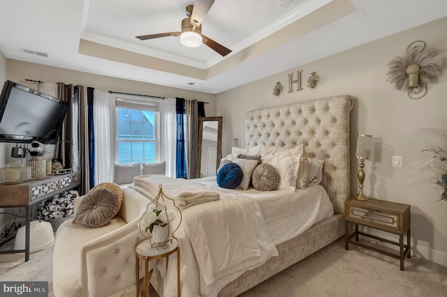 bedroom with a ceiling fan, visible vents, a tray ceiling, ornamental molding, and carpet flooring