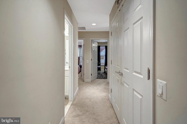 hall featuring visible vents, light colored carpet, and baseboards