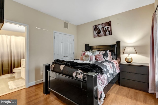 bedroom with visible vents, baseboards, ensuite bath, and wood finished floors