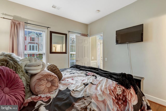 bedroom featuring wood finished floors, visible vents, and baseboards