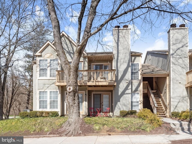 exterior space featuring french doors, a chimney, stairs, and a balcony