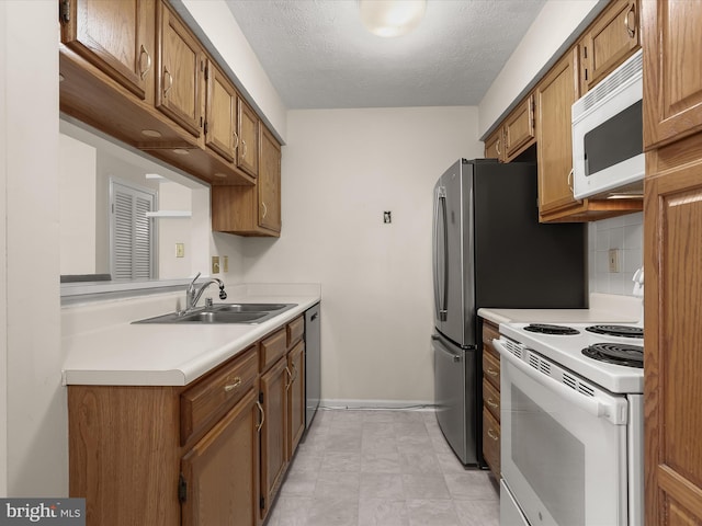 kitchen with a sink, white appliances, brown cabinetry, and light countertops