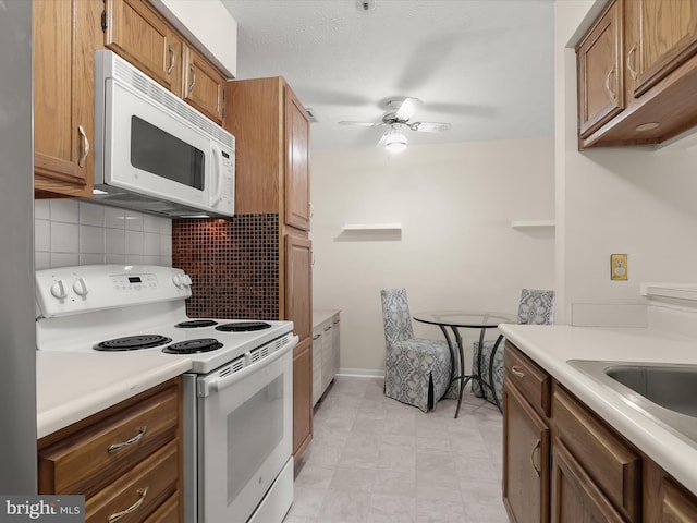 kitchen featuring brown cabinets, backsplash, white appliances, light countertops, and ceiling fan