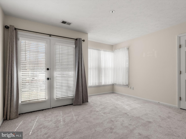 carpeted spare room featuring visible vents and baseboards