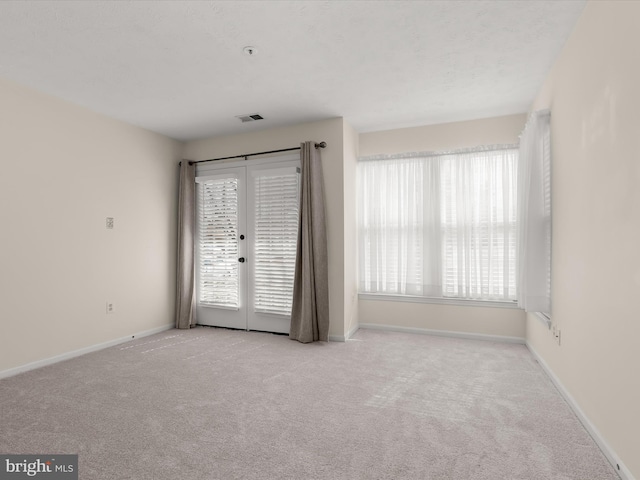 unfurnished room with carpet flooring, baseboards, visible vents, and french doors