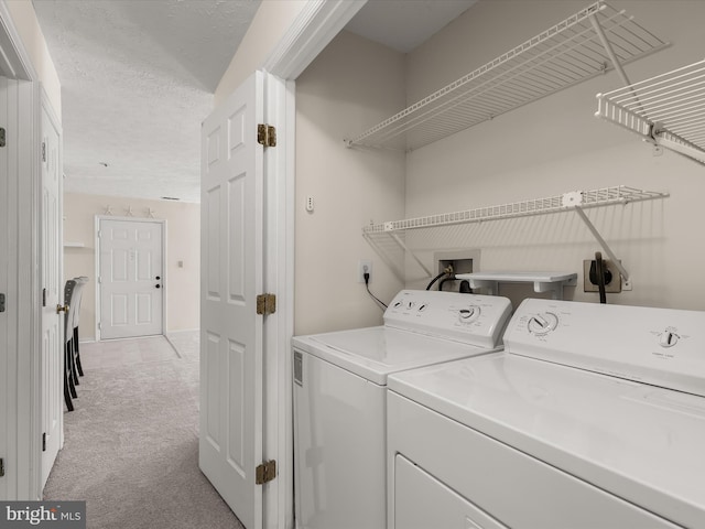 laundry room featuring a textured ceiling, laundry area, separate washer and dryer, and light carpet