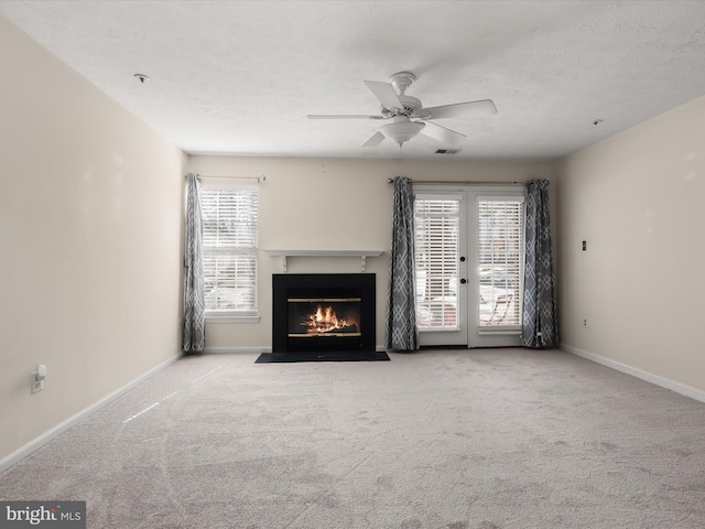 unfurnished living room featuring baseboards, carpet floors, ceiling fan, french doors, and a textured ceiling