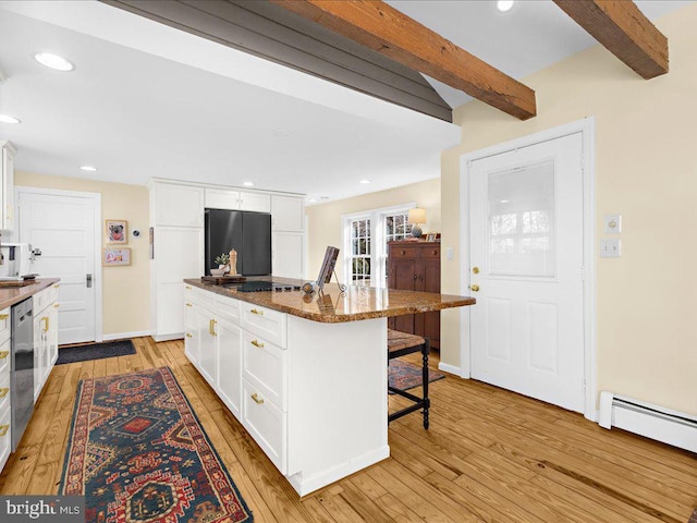 kitchen featuring appliances with stainless steel finishes, beamed ceiling, a kitchen bar, and white cabinets