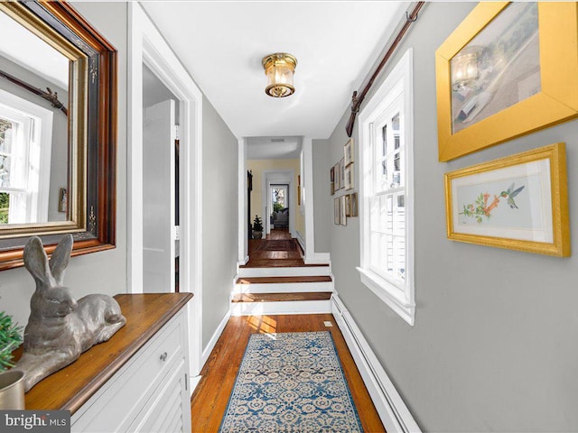 hallway with a baseboard radiator, baseboards, and wood finished floors