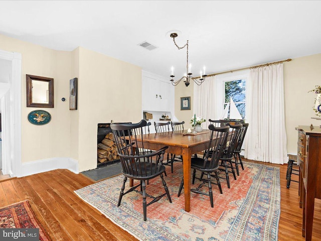 dining room with visible vents, a notable chandelier, baseboards, and wood finished floors