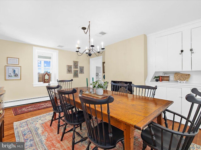 dining room featuring visible vents, baseboard heating, wood finished floors, and a chandelier