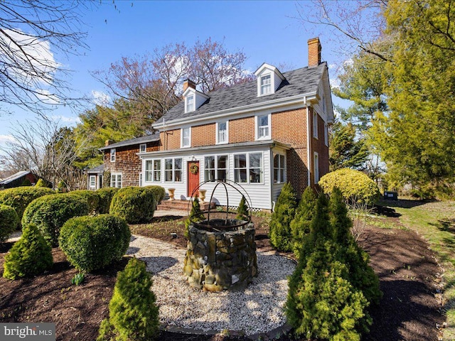 rear view of property with brick siding and a chimney