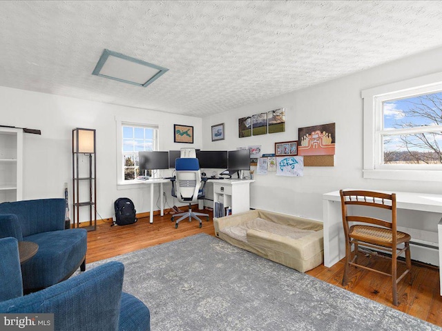 office featuring attic access, a textured ceiling, baseboards, and wood finished floors