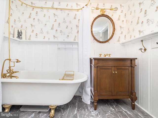 bathroom with wallpapered walls, marble finish floor, a wainscoted wall, and a soaking tub