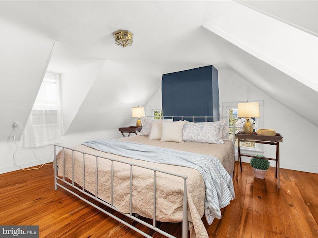 bedroom with wood-type flooring, baseboards, and vaulted ceiling