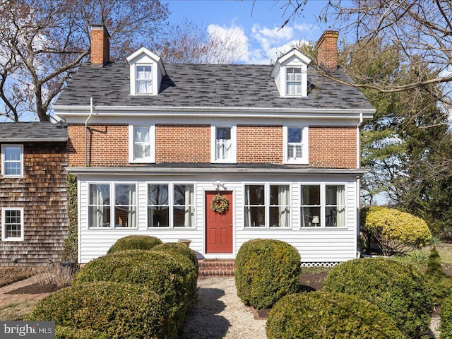 view of front facade featuring a chimney and brick siding