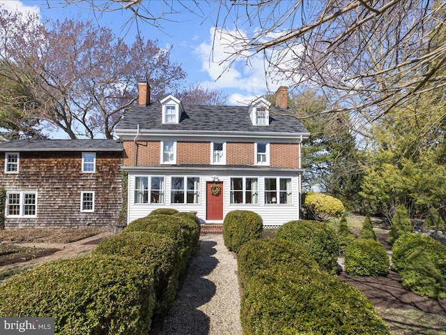 view of front of property with a shingled roof and a chimney