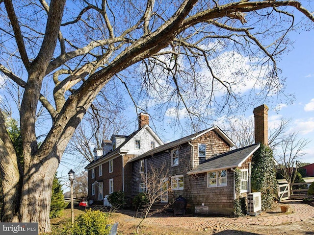 view of side of property with ac unit and a chimney