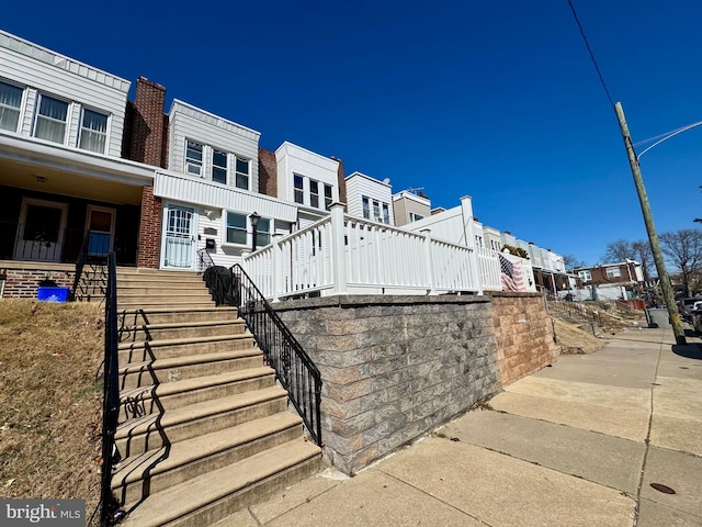 view of property exterior featuring covered porch, a residential view, and brick siding