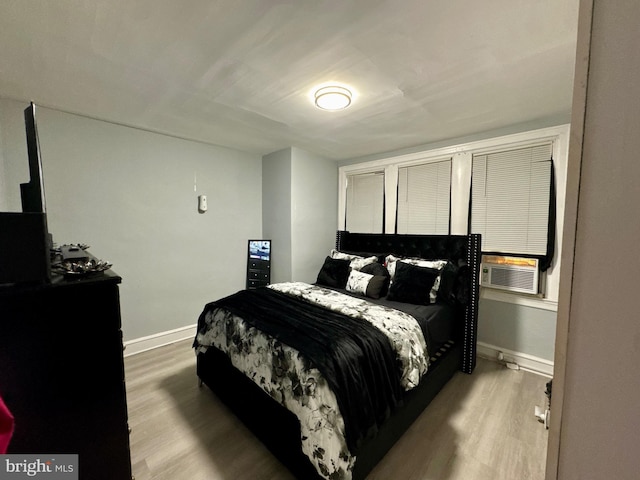 bedroom featuring cooling unit, baseboards, and wood finished floors