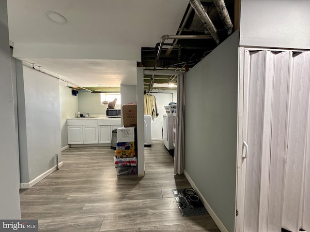 hall with washer and dryer, a sink, baseboards, and wood finished floors