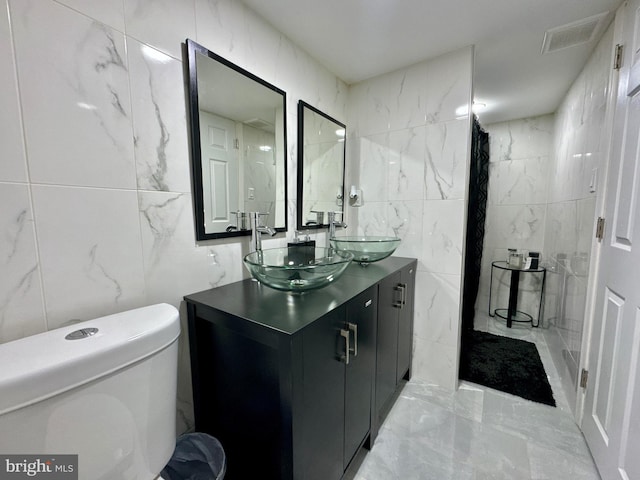 bathroom with toilet, marble finish floor, visible vents, and a sink