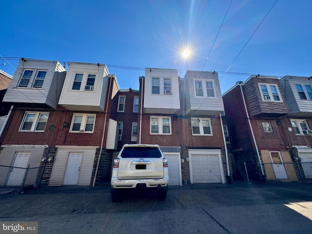 multi unit property with brick siding, an attached garage, and fence