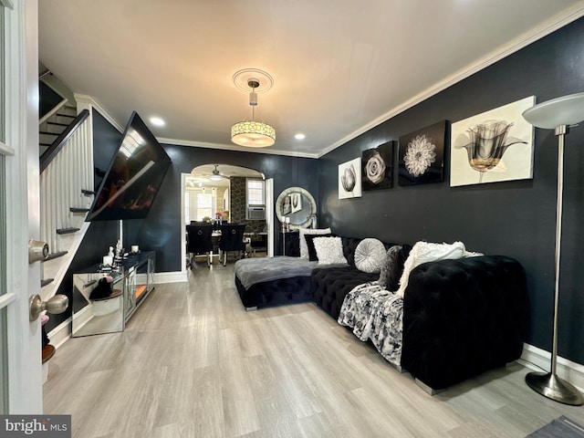 bedroom featuring baseboards, crown molding, arched walkways, and wood finished floors