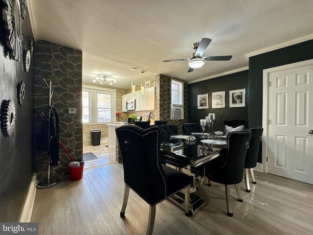 dining space featuring light wood finished floors, ornamental molding, ceiling fan, a stone fireplace, and cooling unit