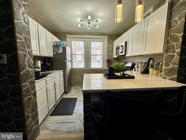 kitchen featuring a peninsula, a sink, white cabinets, light countertops, and appliances with stainless steel finishes