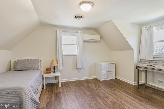 bedroom featuring visible vents, baseboards, lofted ceiling, a wall unit AC, and wood finished floors