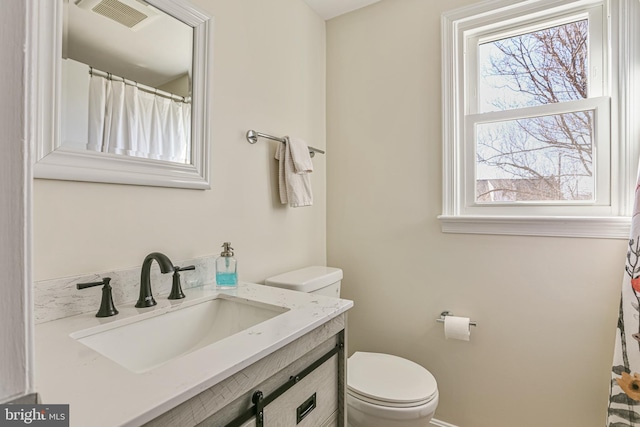 bathroom featuring vanity, toilet, and visible vents