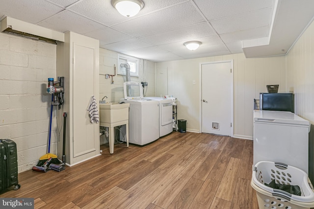 washroom featuring laundry area, concrete block wall, wood finished floors, and washer and clothes dryer