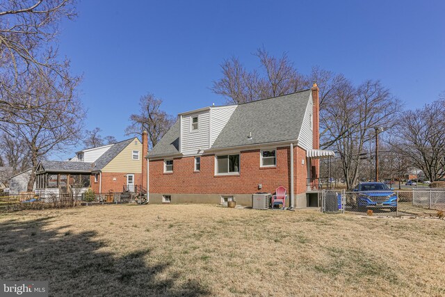 rear view of property with central AC, fence, a yard, brick siding, and a chimney