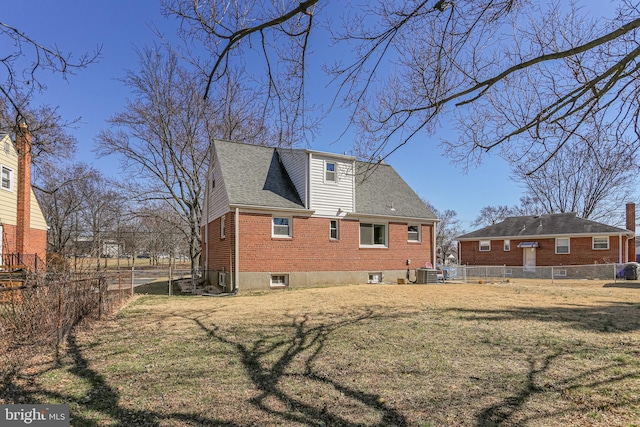 back of house with a lawn, roof with shingles, brick siding, central AC unit, and fence private yard