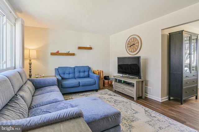 living area with visible vents, baseboards, and wood finished floors