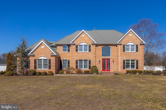 view of front of house featuring a front yard, brick siding, and fence