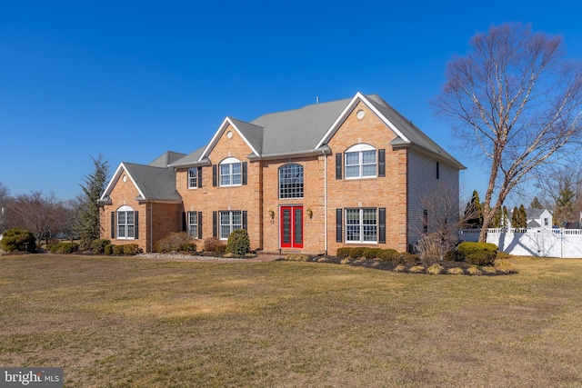 view of front of house featuring a front yard, a gate, brick siding, and fence