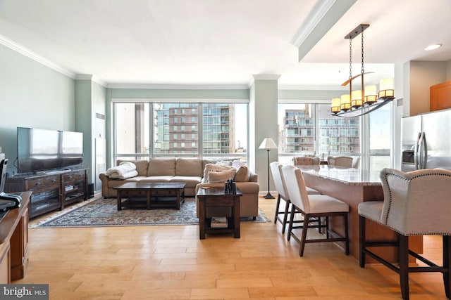 living area with crown molding, light wood finished floors, and an inviting chandelier