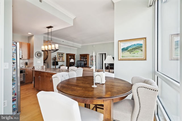 dining area with light wood finished floors, a baseboard radiator, ornamental molding, and a chandelier