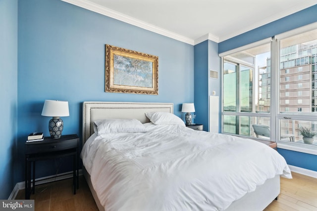 bedroom with crown molding, baseboards, and wood finished floors