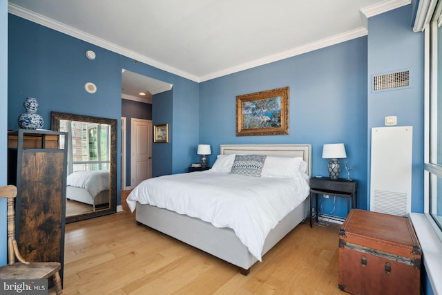 bedroom featuring visible vents, wood finished floors, and ornamental molding