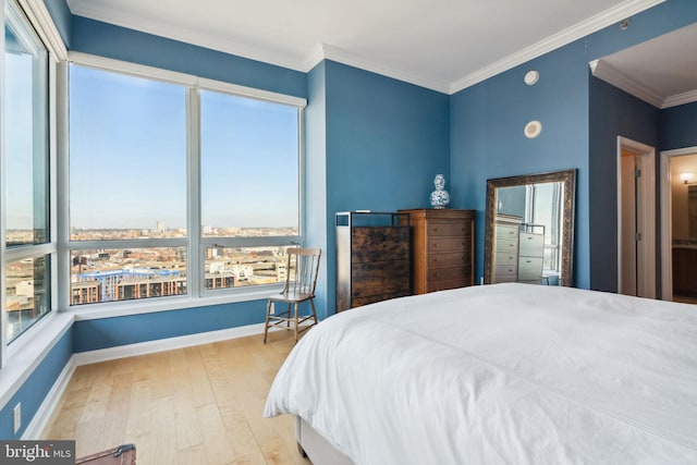 bedroom featuring baseboards, a view of city, ornamental molding, and wood finished floors