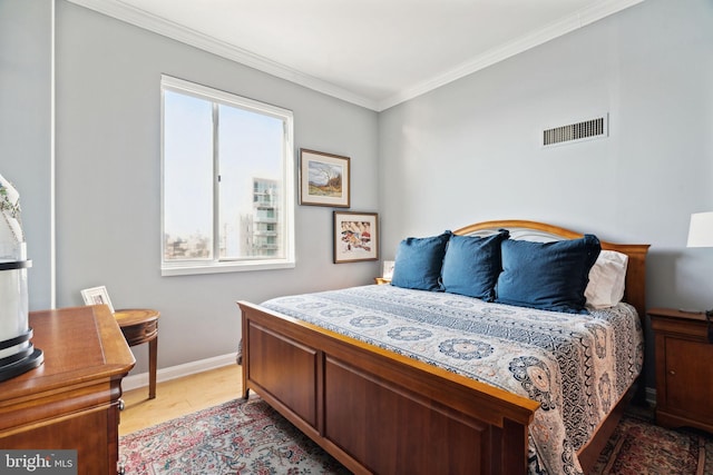 bedroom with light wood-style floors, visible vents, crown molding, and baseboards