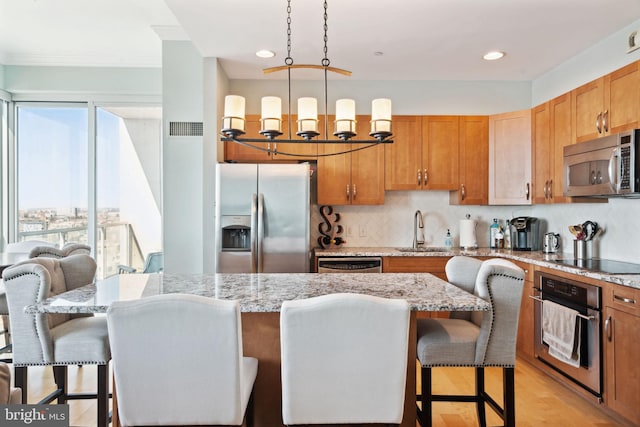 kitchen with tasteful backsplash, a kitchen breakfast bar, decorative light fixtures, stainless steel appliances, and a sink