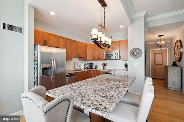 kitchen with stainless steel appliances, visible vents, a sink, and a kitchen bar